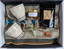 Load image into Gallery viewer, We are ready to cuddle up and keep warm with our cozy and snug gift box.    This gift includes a Treeline Collective Oatmeal blanket, Emily Tolmie Mugs, Hollow Tree Travel Candle and an air plant.     Our gifts come beautifully wrapped with a bow along with an gift card including your personalized note.  air plant  hand made in squamish  squamishpots  squamish cups  squamish mugs  squamish blanket  squamish tea  lucas teas  gift of warmth  blanket gift  tea gift  tea  treeline collective blanket  treeline c
